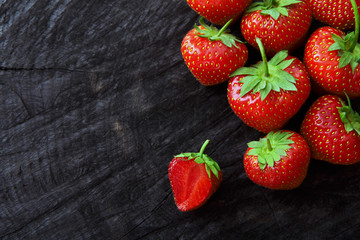 Red fresh strawberries on black rustic wood background