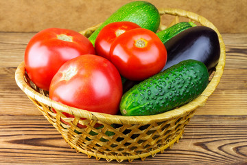 Group of backyard vegetables in wicker basket on wooden background.