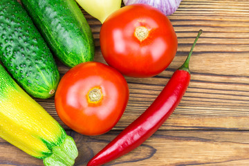 Backyard vegetables, tomatoes, cucumber, garlic, pepper, zucchini on wooden background.