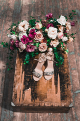 Bride shoes with jewels and surrounded by flowers arrangement