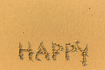 Happy - hand-drawn in gentle sea beach sand.
