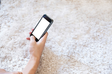 Hand using smart phone on white carpet, selective focus