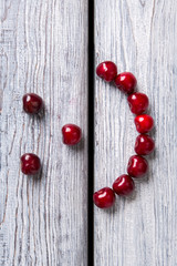 Smiley face made of cherries. Red fruit on wooden background. Stay healthy and be happy. Art is closer than ever.