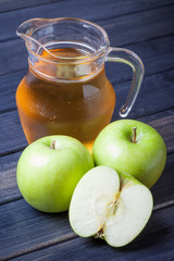 Apple juice in pitcher on table, vertical still life