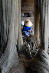 Vietnamese woman sewing fishing net
