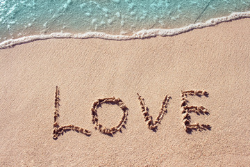 Love handwritten on a tropical beach