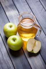 Cold apple juice in pitcher on table, vertical top view morning still life