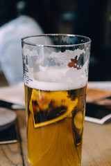 Glass of lager beer half-full in a restaurant interior