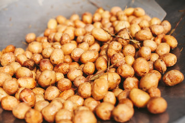 Young potatoes fried in boiling oil to a large frying pan over an open fire