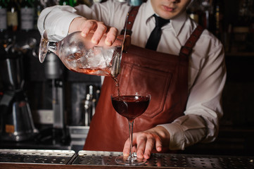 Bartender pouring fresh cocktail in fancy glass