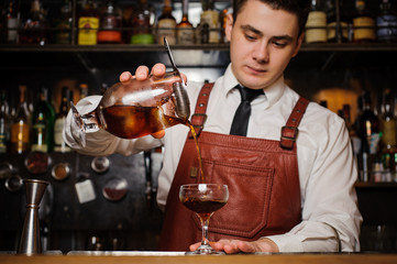 Bartender pouring fresh cocktail in fancy glass