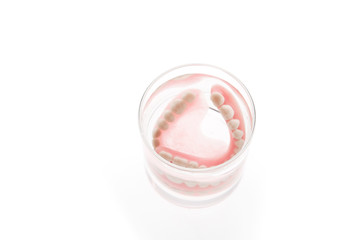 Denture in glass of water on white background