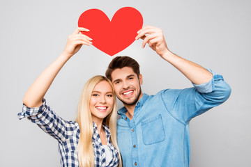 Young smiling family holding paper heart under head