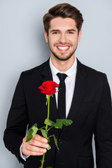 Handsome businessman with beaming smile holding red rose