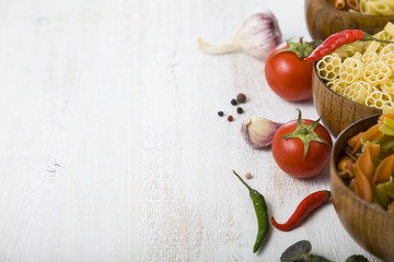Raw pasta and spices in wooden bowls
