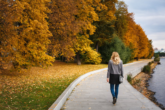 Full body of woman walking in autumn park