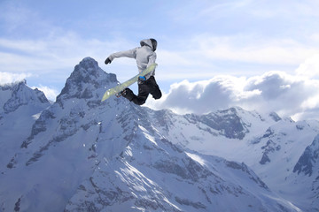Snowboarder jumps high in the mountains.