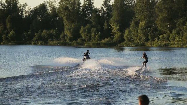 Jet Ski and a girl water skiing on the lake.Water skiing and have fun.Jet ski and water ski.Young girl water skiing on a lake.