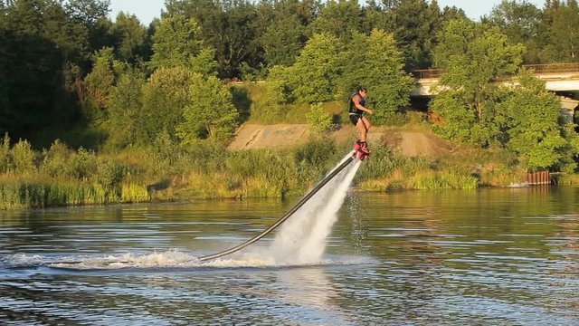 Man on the flying board on the river, water jet spray.Man on the flying board flies over the lake water.Fly board rider.new water sport called fly board.