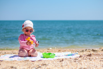 Baby girl playing on the beach near the sea