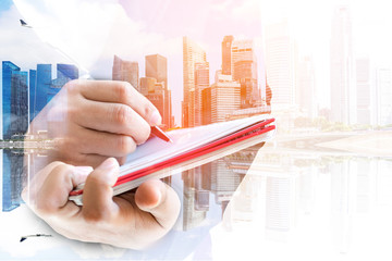 Double exposure of businesswoman  writing the word on a notebook on cityscape background.
