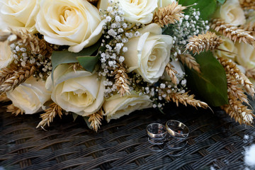 Wedding rings on background of white roses