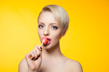studio shot of young blonde girl eating lollipop