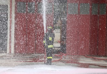 Fototapeta premium brave fireman during the fire drill with the hose foam