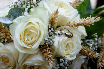 Wedding rings with white roses and wheat