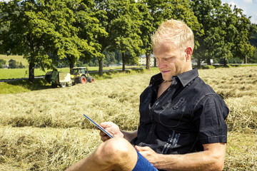 Man with tablet PC in haymaking