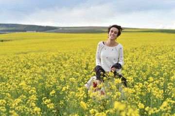 Fototapeta premium Beautiful woman cheering in rapeseed field and enjoying sunny su