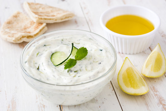 Tzatziki and ingredients on white wooden table

