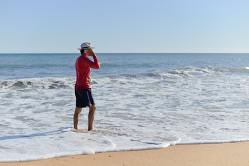 Amazing young male talking on mobile phone, storm wave beach background