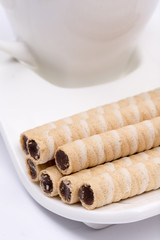 Chocolate wafer cream rolls and white cup of black coffee