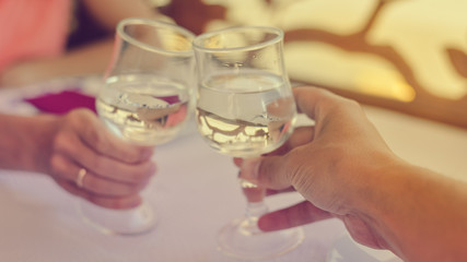 Closeup view of human hand holding glass, restaurant light table background