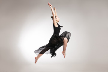 Naklejka premium Young ballet dancer wearing black transparent dress jumping 