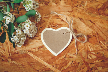 Small Heart Card with White Flowers and Green Leaves on the Texture Wooden Background.Celebrations Wishes