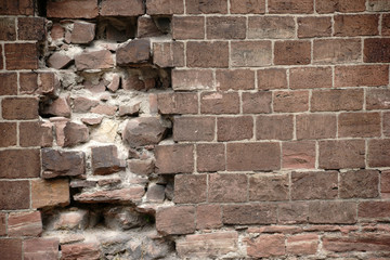 Löcher in der Mauer / Eine Mauer aus markanten roten Steinen mit Beschädigungen und Löchern.