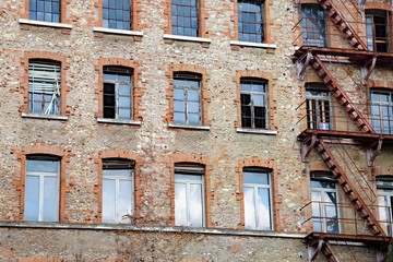 dilapidated industrial building with rusty fire escape with faci