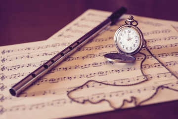 Time for music / Tin whistle on music sheet with vintage pocket watch.