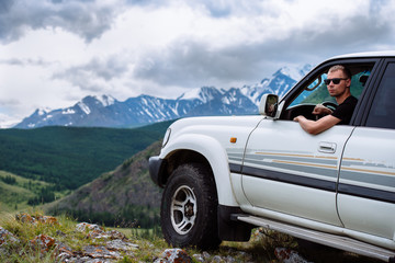 man with glasses in the SUV drove to the edge of the mountain
