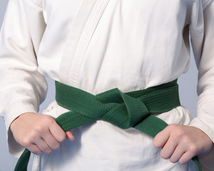 Hands tightening green belt on a teenage dressed in kimono