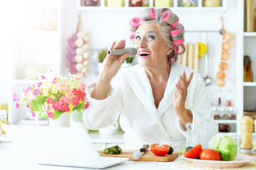 Obraz na płótnie Canvas Senior woman in hair rollers at kitchen