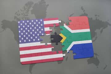 puzzle with the national flag of united states of america and south africa on a world map background.