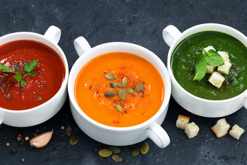 assortment of vegetable cream soup on dark background, top view