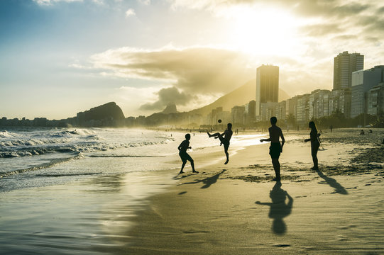 Football altinho silhouettes playing on the shore of Copacabana Beach at sunset in Rio de Janeiro, Brazil 