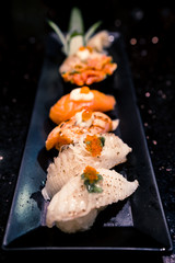 Dish of various sushi types, selective focus point with blur depth of field effect, dark atmosphere