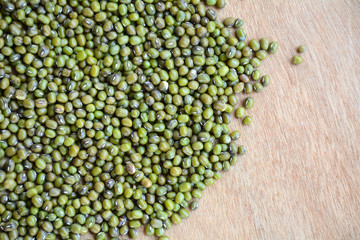 Green bean or mung bean seeds in a cup on a wooden floor.