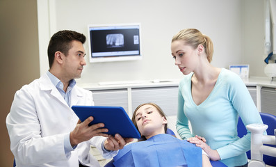 Fototapeta premium dentist showing tablet pc to girl and her mother