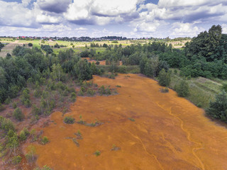 Old sulfuric acid natural tank orange color in south of Poland.